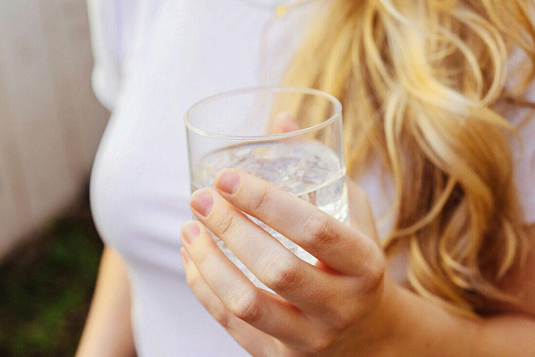 Frau hält gefülltes Wasserglas in der Hand