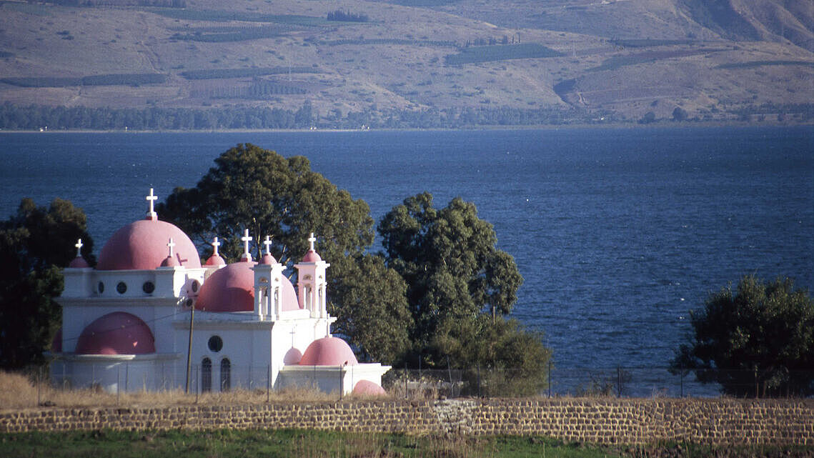 Grosser See mit Bergen im Hintergrund, im Vordergrund eine Kirche mit vielen Kuppeln